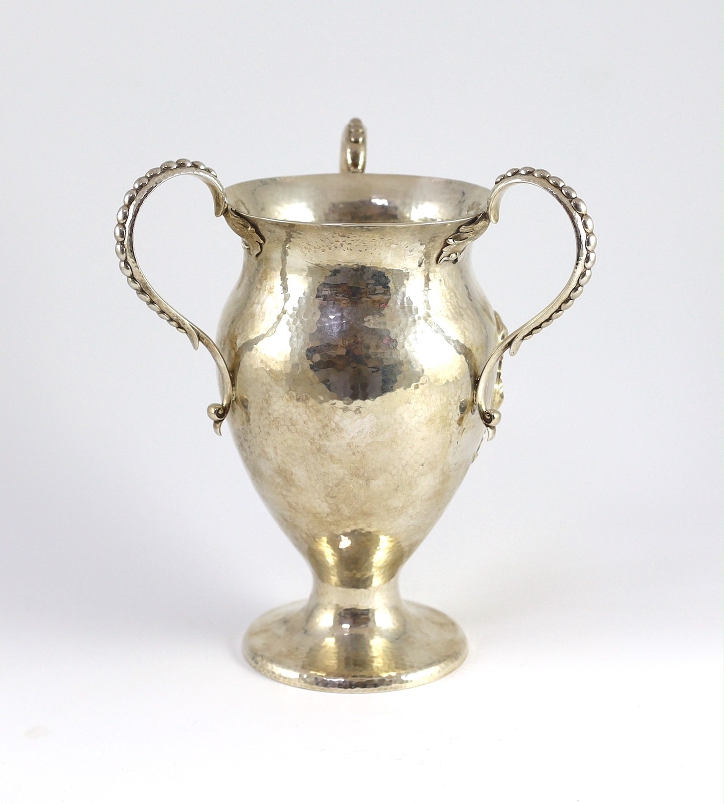 A George V Arts and Crafts planished silver three handled pedestal vase, by Holland, Aldwinckle & Slater